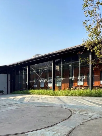 The exterior of the Automobile Design Studio features a massive glass facade, allowing natural light to flood the interior workspaces. This transparency puts the creative process on display and connects the studio to the surrounding campus, including the original vehicle turntable.