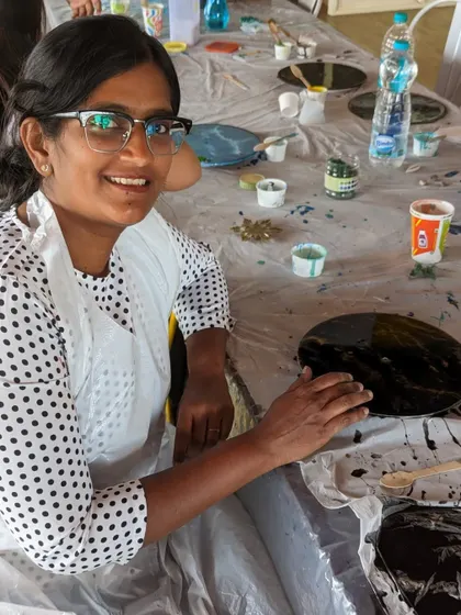 A participant working on a galaxy-themed resin clock, carefully creating a cosmic swirl of colors.