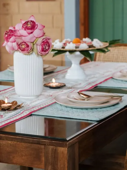 A festive table setting from our Rani Collection shoot. The table runner and placemats feature our signature prints, complemented by fresh lotus flowers and brass candle holders for a touch of traditional elegance.