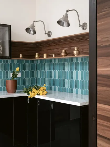 A dry pantry unit outside a bedroom in 'Project Varnika'. The modern finishes with emerald green tiles and black acrylic provide a sophisticated contrast to the home's traditional aesthetic.