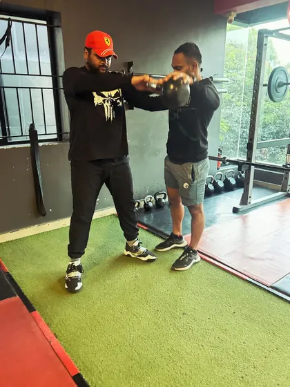 A trainer corrects a client's form during a kettlebell swing, ensuring the movement is both safe and effective.
