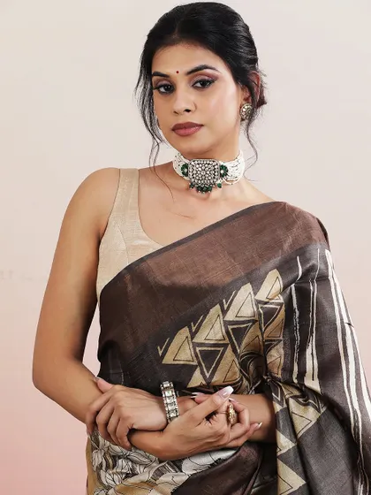 A close-up portrait of the model wearing the brown and beige printed saree, paired with a statement choker.