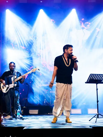 A wide shot of a singer and his band on stage, capturing the scale of the performance and the impressive lighting setup.