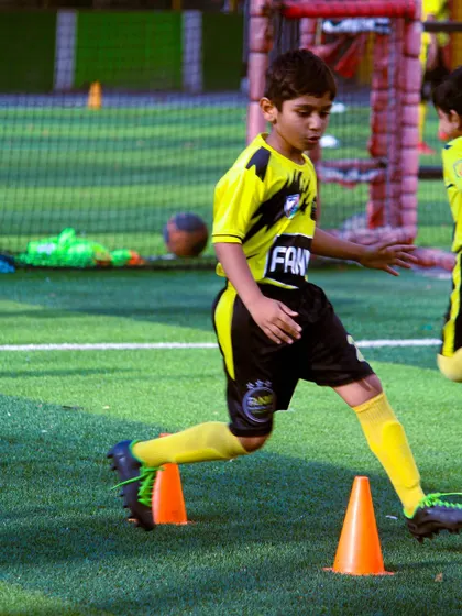 A young player practices quick feet and agility around cones, a fundamental drill for any aspiring footballer.