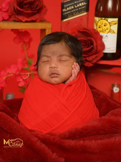 A simple yet powerful shot from the red-themed series. The focus is on the baby's peaceful face amidst the bold color.