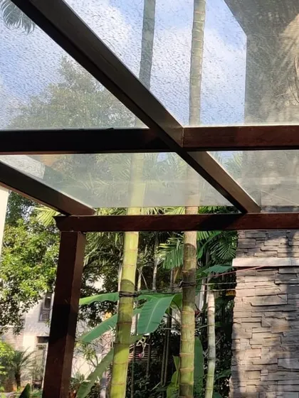 A close-up of a wooden pergola frame with a glass roof, showing how the structure integrates with the surrounding nature. This is the foundation of our elegant and durable sunroom designs.