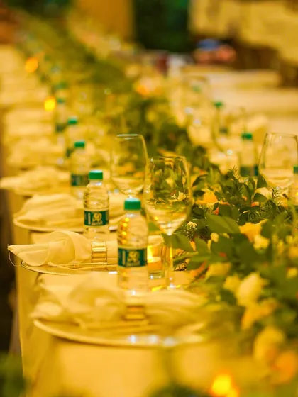A long shot of an outdoor dinner setup, with tables elegantly decorated with floral runners and soft lighting, creating a magical ambiance for an evening celebration.