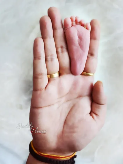 A powerful image showing just how small your newborn is, with their tiny foot resting in the palm of a parent's hand. This shot emphasizes the delicate size of your new baby.