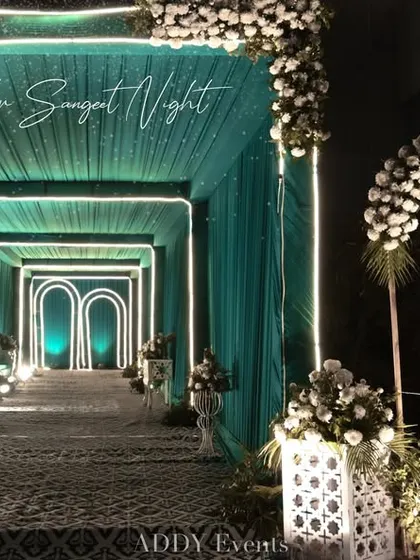 A stunning entrance tunnel designed with teal drapery and illuminated geometric arches. This modern and stylish walkway sets a sophisticated tone for guests as they arrive at a corporate cocktail party or gala.