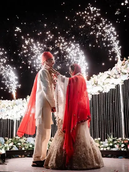 The grand Varmala exchange, complete with fireworks. This shot captures the scale and excitement of the ceremony, freezing a spectacular moment in time against the night sky.
