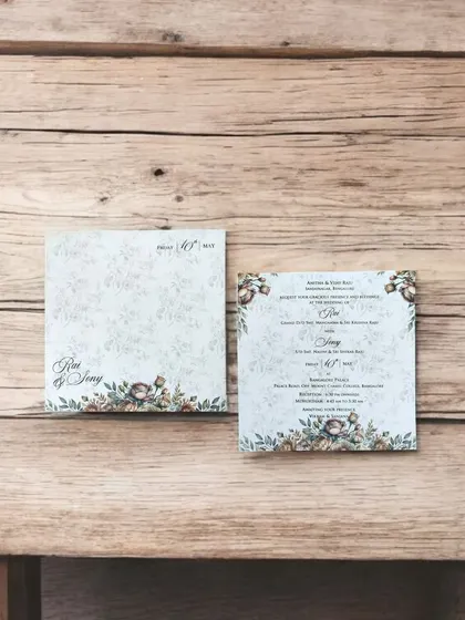 A simple and elegant invitation on textured paper with a subtle floral border, perfect for a minimalist wedding.
