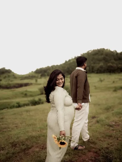 A classic "follow me" style shot. She looks back with a warm smile while leading him by the hand, symbolizing their journey into parenthood together.