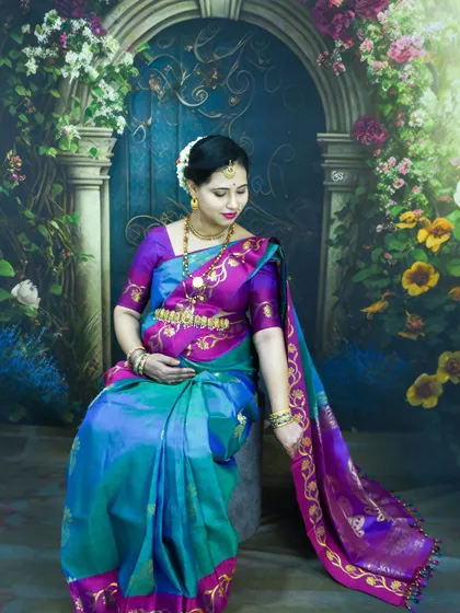 An elegant, seated portrait of a mom-to-be in a traditional blue and purple silk saree in our studio.