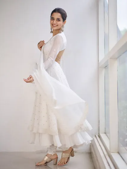 The full view of the off-white Anarkali shows its layered, tiered skirt which adds beautiful movement. The open back gives this traditional outfit a surprising and modern update.