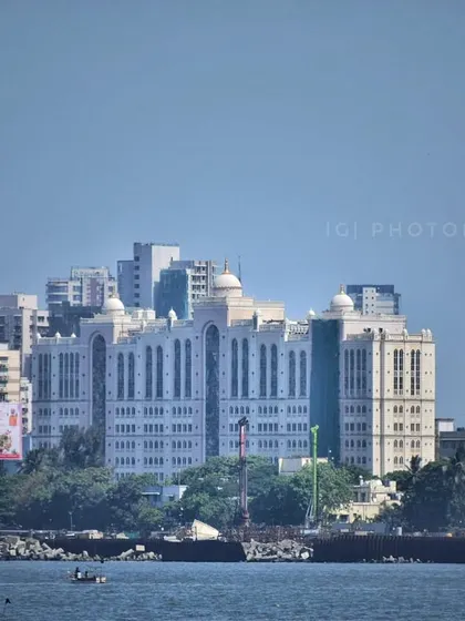 A view of a prominent hospital building in Mumbai from the sea, showcasing its large and distinct architecture against the city skyline.