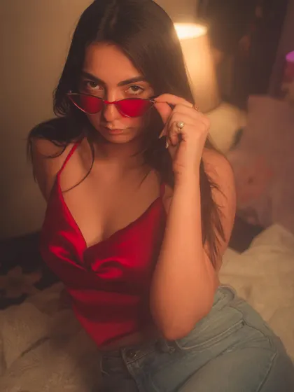 A seductive look over a pair of red sunglasses. This indoor shoot has a very intimate and moody vibe.