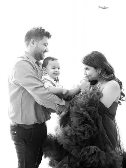 A candid black and white photo capturing a sweet interaction between parents and their baby. Sometimes the most beautiful moments are the ones in between poses.