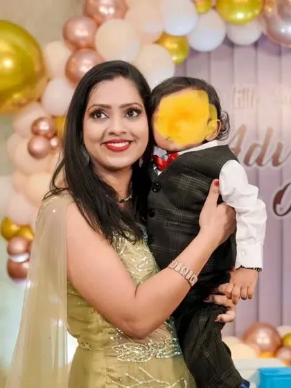 The beautiful client from the testimonial, celebrating her son's birthday. Her makeup features a classic winged liner and a bright red lip, looking fresh and radiant for the party.