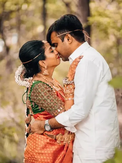 A passionate kiss between a newly married couple in the woods, still in their beautiful wedding attire.