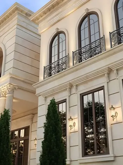 An upward view of the facade, highlighting the detailed cornices, arched windows, and wrought-iron balcony railings.