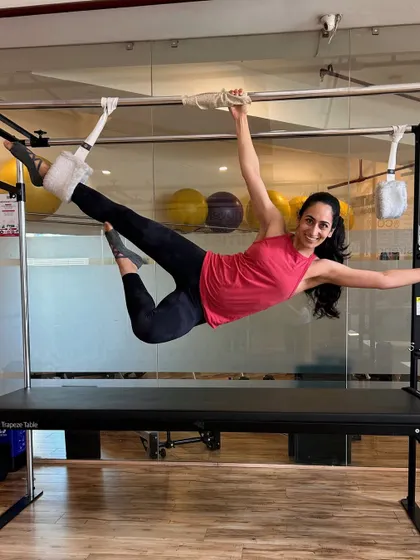 A client hangs gracefully from the Cadillac, a move that requires immense core and upper body strength.