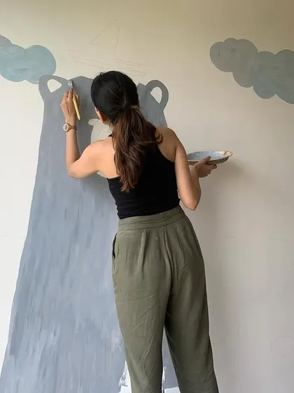 Painting the clouds above the bear mural. The soft, simple clouds add to the dreamy, storybook quality of the artwork.
