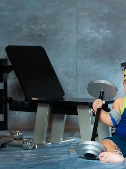 This little one is serious about his fitness, holding a dumbbell with a determined look. A great shot for fitness-loving families.