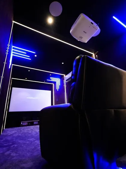 A view from the side of the recliners, showing how the linear lighting on the walls and ceiling creates a sense of depth and a futuristic feel.