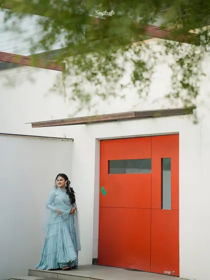 The bride stands by a bold red door, her soft blue dress creating a striking color contrast in this modern architectural portrait.