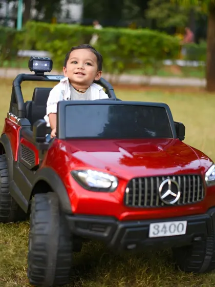 A solo shot of the little boy enjoying his ride-on Mercedes. His happy smile says it all.