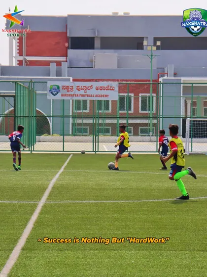 Success is nothing but hard work. A player on the attack during a game, with the Nakshatra Football Academy banner in the background.