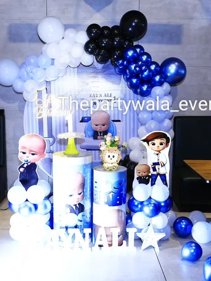 A stylish Boss Baby theme with a unique black, white, and blue balloon arrangement. The shirt and bow tie backdrop adds a very clever and thematic touch.