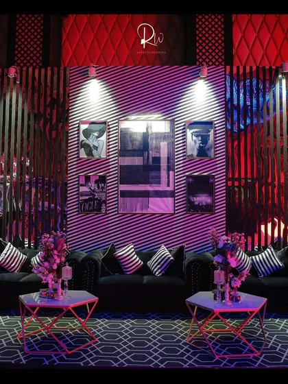 A chic lounge area for a cocktail party, with black tufted sofas, geometric-patterned carpets, and modern art on the walls.