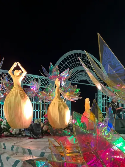 The full varmala stage at night, with the dancing dolls and lotus flowers creating a spectacular, multi-dimensional display of light and color.