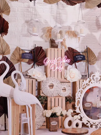 This photo booth is all about the boho vibe. I layered wooden crates, dried palm leaves, macrame details, and flamingo statues to create a highly textural and visually interesting entrance decor.