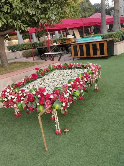 A traditional 'manji' or charpai decorated beautifully with red and white flowers. This can be used as a prop for a Mehandi function or as a unique seating element.
