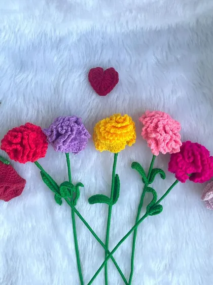 A row of single-stem crochet carnations in different colors, along with a few rosebuds. They look so pretty lined up together.