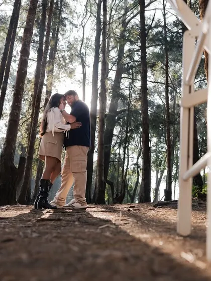 A creative composition, framing the couple between two chairs in the middle of the woods. This adds a touch of surrealism and focus to their intimate moment.
