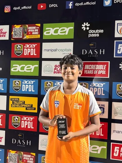 A young player proudly holds his award after a competitive match in the DPDL, a league designed for youth talent development.