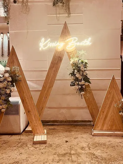 We specialize in creating elegant and memorable milestone celebrations. This custom-built "Kissing Booth" photo-op, featuring a neon sign and floral arrangements, served as a chic centerpiece for a 25th-anniversary party.