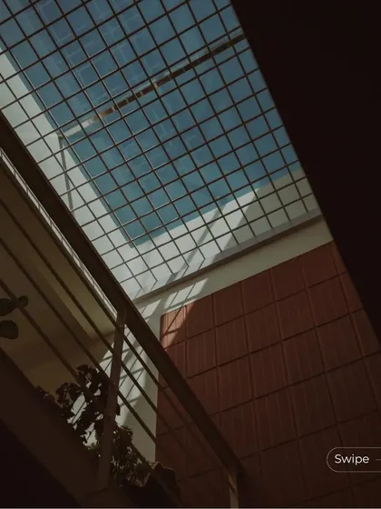 A view up towards the sky through a wire-mesh covered skylight, with the surrounding terracotta walls adding warmth to the space.