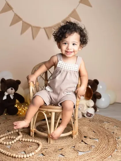 That toothy grin is everything! This little boy is having so much fun during his milestone session, surrounded by teddy bears and a cozy, neutral setup.