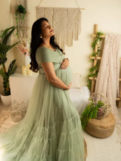 A serene, sun-kissed moment. The mother-to-be enjoys a quiet moment, beautifully lit in the studio's natural light corner.
