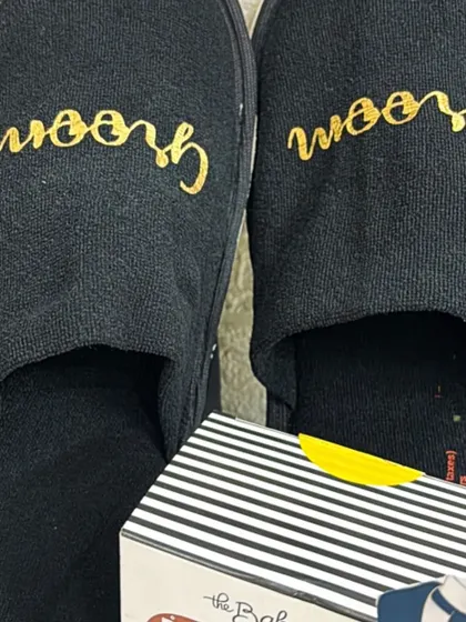 A close-up of the personalized 'Groom' slippers, a comfortable and stylish part of the groom's pre-wedding gift hamper.