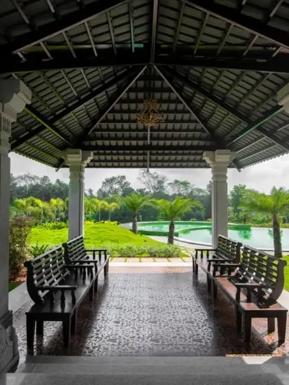 A covered gazebo with stone pillars offers a shaded spot to rest and enjoy views of the pool and surrounding gardens.