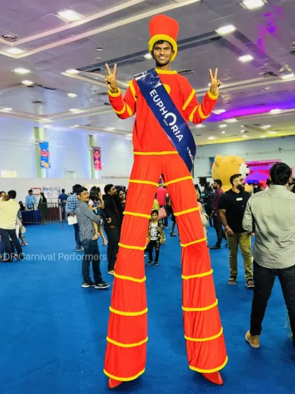 Taking things to new heights! Our stilt walker, dressed in a bright red costume, rises above the crowd at an indoor event, bringing a unique and unforgettable performance.