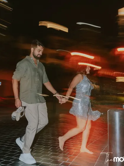 A fun, candid shot of a couple running barefoot through the streets of Dubai at night. The motion blur from the city lights adds a dynamic and energetic feel to this spontaneous moment.