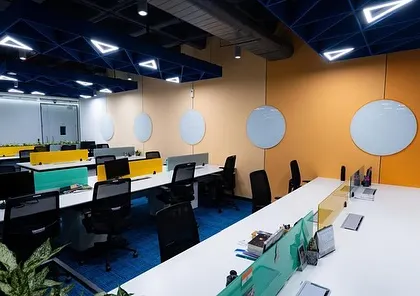 An open workspace at Tata Consumer Products, where the long lines of desks are softened by the presence of plants. This design promotes a sense of openness while still providing visual comfort.