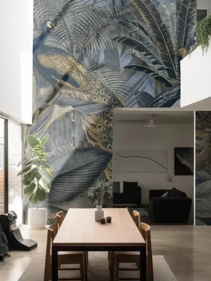 A luxurious and dramatic wallpaper featuring a golden peacock amidst dark tropical foliage. This design, installed on a double-height wall, creates a stunning statement of opulence and artistry.