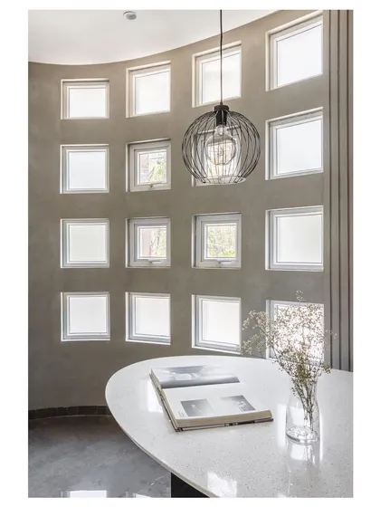 Inside the 'House Under Tabebuia Trees', this dining nook is defined by a curved wall with a grid of small windows. Our guiding principle here was 'If Light defines a space, Colours define sense'. The design manipulates natural light to create a serene, almost surreal experience for the inhabitants.